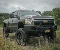 a large black truck parked on top of a grass covered field