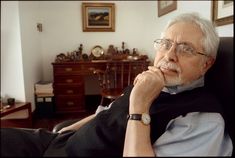 an older man sitting in a chair with his hand on his chin