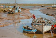 there are many small boats in the water at low tide, and one is pulling it up to shore