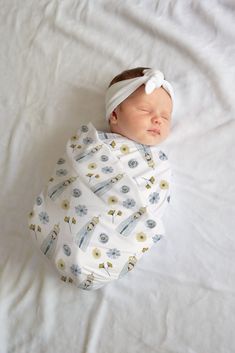 a newborn baby wrapped in a swaddle on top of a white bed sheet