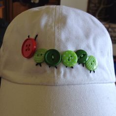 a white hat with three green and red buttons attached to the front of it, sitting on top of a table