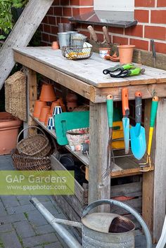 an outdoor garden table with gardening utensils on it