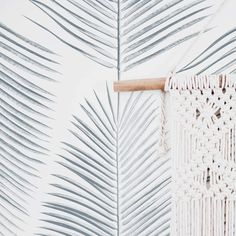 a white wallpaper with palm leaves on it and a wooden stick in the middle