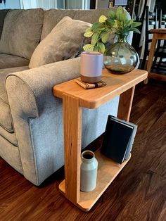 a living room with a couch, coffee table and vase on the end shelf next to it