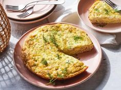 an omelet is on a pink plate next to two plates with silverware