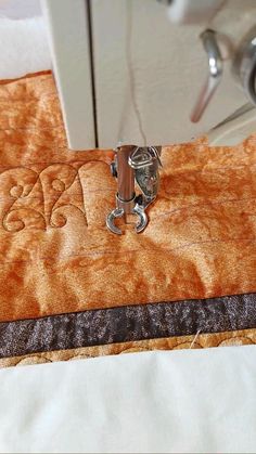 the sewing machine is working on an orange piece of fabric that has been sewn