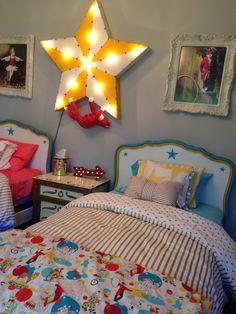 two beds in a room with pictures on the wall above them and one has a star shaped light