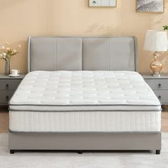 a bed with a white mattress sitting on top of it next to a night stand