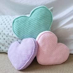 three crocheted heart pillows sitting on top of a bed