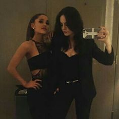 two beautiful women taking a selfie in front of a mirror with their cell phone