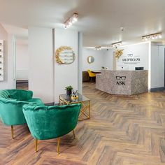 an office with two green chairs in front of a reception desk and large mirror on the wall