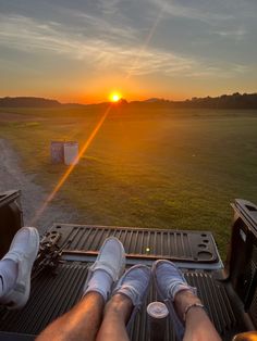 two people sitting in the back of a pickup truck with their feet on the bed