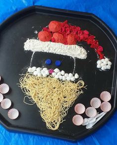 a black tray topped with pasta, shells and red flowers on top of blue table cloth