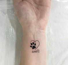 a small tattoo on the wrist of a person with a dog's paw and heart