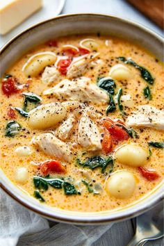 a bowl of soup with chicken, spinach and tomatoes