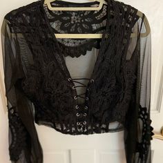 Never Worn Black Crop Top That’s See-Through With Lacing In The Front And Flowery Detailing Gothic Black Blouse For Night Out, Black Lace Crop Top For Spring, Black Lace Long Sleeve Top, Fitted Black Lace Blouse, Black Lace Crop Top For Party, Black Lace Crop Top For Night Out, Gothic Lace Top For Night Out, Gothic Black Crop Top For Spring, Black Gothic Crop Top For Spring