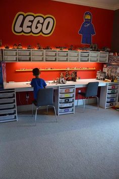 a young boy sitting at a desk with legos on the wall behind him in a playroom