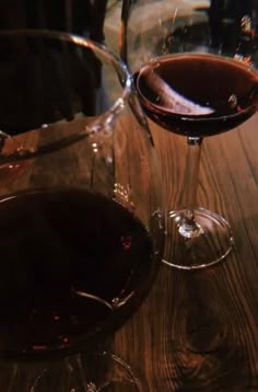 two glasses of wine sitting on top of a wooden table next to eachother