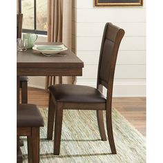 a dining room table with two chairs and a plate on top of the wooden table