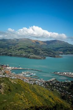 an aerial view of a city and water with mountains in the background on a sunny day