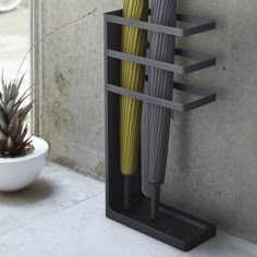 two umbrellas are placed on a stand next to a potted plant