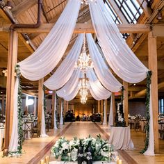 an indoor wedding venue with white draping and chandelier