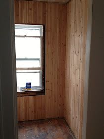 an empty room with wood paneling on the walls and a window in the corner