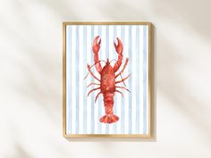 a red lobster on a blue and white striped background in a wooden frame hanging on the wall