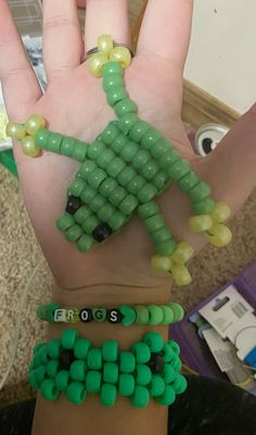 a person's hand with green beads and bracelets on it that are made to look like a palm tree