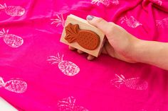 a person is holding a rubber stamp with pineapples on it and pink fabric