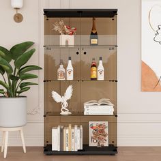 a shelf with bottles and books on it in front of a wall mounted art piece