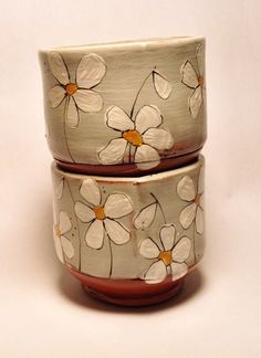 two bowls with flowers painted on them sitting next to each other in front of a white background