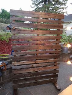 a wooden fence made out of pallets with lights on the ground and trees in the background