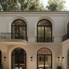 a large white building with arched windows and doors on the outside, surrounded by greenery