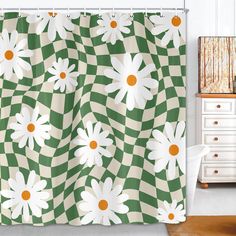 a green and white shower curtain with daisies in the center on a checkered background