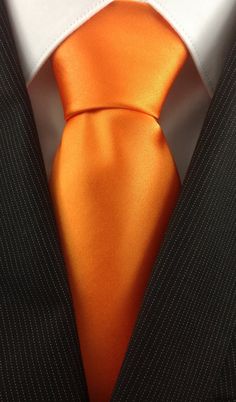 an orange tie is worn by a man in a suit