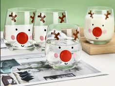 three glasses with reindeer faces on them are sitting on a table next to a magazine