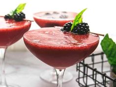 three glasses filled with red drink and garnished with blackberries