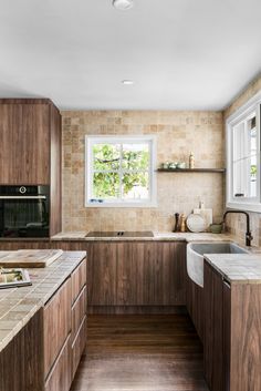 a kitchen with wooden cabinets and marble counter tops, along with a window over the sink