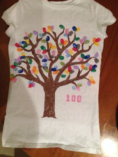 a t - shirt with a tree on it that has the number 100 painted on it