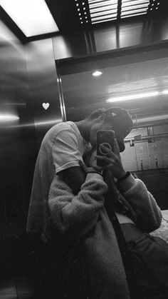 black and white photograph of a man sitting on a bench looking at his cell phone