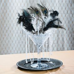 a glass vase filled with feathers on top of a table