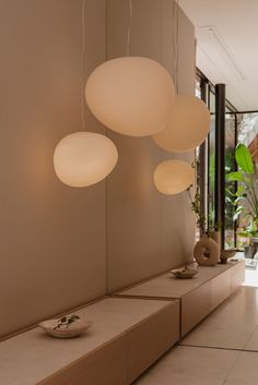 three white lights hanging from the ceiling in a room with beige walls and flooring