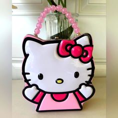 a hello kitty purse sitting on top of a table next to a vase with flowers