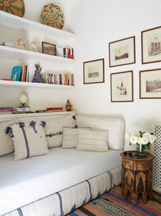 a living room with white couches and pictures on the wall above them, along with bookshelves