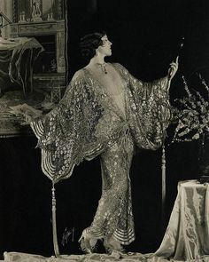 an old fashion photo of a woman standing in front of a table with flowers on it