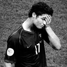 black and white photograph of a soccer player holding his head in one hand while standing on the field