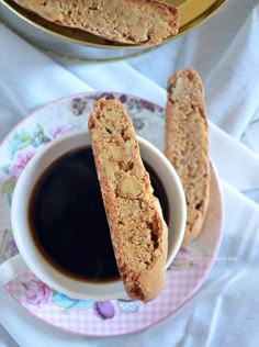 two pieces of bread sitting on top of a plate next to a cup of coffee