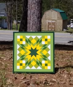 a green and yellow quilt sitting next to a tree