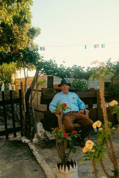 a man sitting on a bench next to flowers and plants in a potted planter